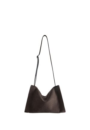 Sac à bandoulière en cuir noir avec une fine sangle réglable suspendu sur un fond blanc.