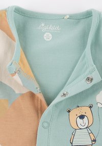 Light teal cotton onesie with a bear illustration. Features snaps at the collar and a color-block design in tan and cream.