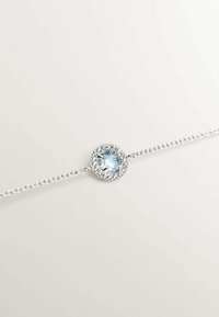 Pulsera de plata con una piedra redonda de color azul claro rodeada de cristales transparentes, con un diseño de cadena delicada.