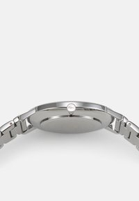 Reloj de acero inoxidable plateado con caja redonda, superficie pulida y brazalete de eslabones. Incluye un detalle de corona redonda. Diseño minimalista.