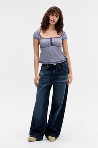 Gestreepte, korte mouwen top met knoopdetails in blauw en wit, gecombineerd met wijde, donkere spijkerbroeken met voorkantzakken en een relaxte pasvorm.