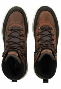 Scarpe da trekking in pelle marrone con collare imbottito, tessuto testurizzato, occhielli metallici e suola in gomma bianca. Marchio Geox visibile all'interno.
