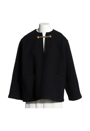 Czarna kurtka z długim rękawem, z przednimi naszywanymi kieszeniami i złotym łańcuszkiem jako zapięcie przy otwartym kołnierzu, wyświetlana na białym torsie manekina.