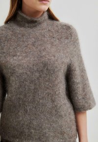 Rjav, puhast turtleneck pulover s kratkimi rokavi, izdelan iz mehkih materialov; ima rahlo ohlapen kroj in teksturirano površino.