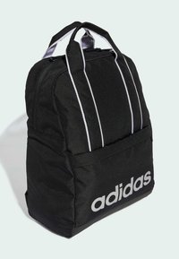 Mochila negra con dos franjas blancas, compartimento principal con cremallera, bolsillo frontal y gran logo blanco de "adidas" en la parte frontal. Tela texturizada.