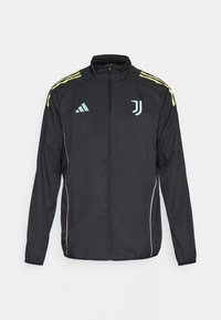 Veste de survêtement noire avec des rayures jaunes sur les épaules. Dotée d'une fermeture éclair à l'avant, d'un logo Adidas bicolore, d'un blason de la Juventus et d'accents roses sur les côtés.