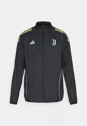 Sort træningsjakke med gule skulderstriber. Har en lynlås foran, to-farvet Adidas-logo, Juventus-emblem og lyserøde sidelæg.