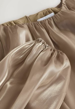 Bronze satin bluse med elastiske samlinger ved udskæringen og ærmekanterne, hvilket skaber et struktureret udseende. Lynlåslukning på ryggen.