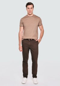 Brązowa bawełniana koszulka z krótkim rękawem, w połączeniu z ciemnobrązowymi spodniami i białymi trampkami. Prosty wzór o klasycznym kroju.