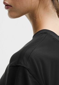 Fekete rövid ujjú ing, kerek nyakkivágással, sima textúrával és látható varrási részletekkel a vállvarráson.