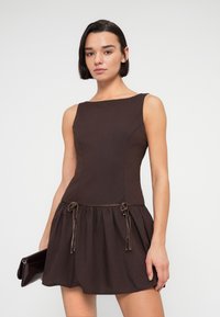 Καφέ φόρεμα γραμμής Α με εφαρμοστή μπούστα και φούστα που ανοίγει. Διαθέτει ρυθμιζόμενα κορδόνια στη μέση και λεία υφή.