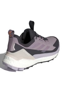 Fialovo-čierny športový topánok s textúrovaným zvrškom, brandingom Gore-Tex, hrubou bielou medzipodrážkou a jedinečným dizajnom päty pre stabilitu.