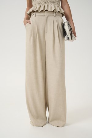 Beige wide-leg trousers made of textured fabric, featuring front pleats and two side pockets, paired with a patterned clutch.