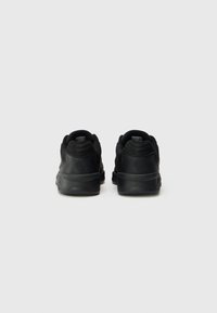 Black athletic shoes with a textured surface, padded collar, and rubber soles. Logo embossed at the heel, designed for comfort and support.
