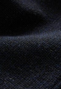 Țesătură texturată în nuanțe de albastru închis, cu o țesătură din tricot fin și o suprafață moale și pufoasă, având variații subtile de culoare.