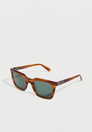 Gafas de sol rectangulares de carey marrón con lentes verde oscuro y acentos metálicos en las patillas, colocadas sobre una superficie blanca.