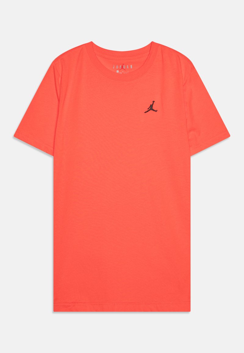 Tričko s krátkým rukávem ve světlém korálovém materiálu, které má na hrudi černé logo Jumpman a kulatý výstřih s hladkou texturou.