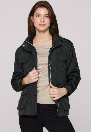 Black nylon jacket with snap buttons, two front pockets, and adjustable cuffs. Features a zip front and a stand-up collar. Smooth texture.