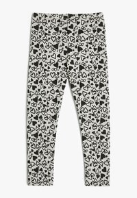 Grå tætsiddende leggings med et mønster af sorte fyldte og omridsede hjerter i forskellige størrelser.