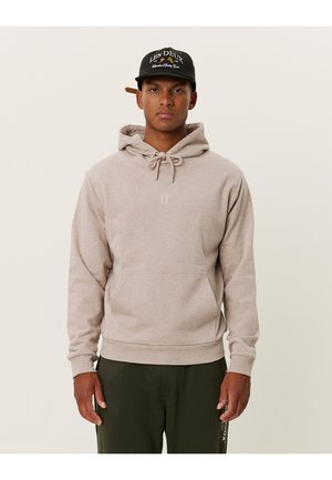 Helle beige Kapuzenpullover mit Kordelzug, Taschen auf der Vorderseite und minimalem Branding. Weicher Stoff und normale Passform, kombiniert mit dunkelgrünen Hosen.