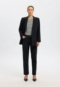 Fekete blézer fekete-fehér csíkos inggel, fekete egyenes szabású farmerrel és fekete, hegyes orrú magassarkúval. Egyszerű kialakítás és szerkezet.