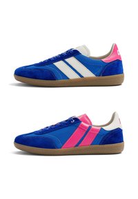 Paire de baskets bleues avec semelles en gomme, bandes latérales blanches et roses, et accents rose et blanc au talon, montrées en profils latéraux orientés dans des directions opposées.