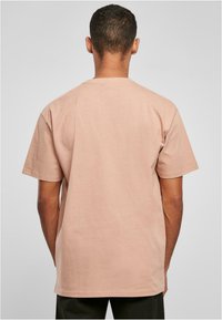 Kortermet t-skjorte med rund hals i lys rosa bomull; glatt tekstur; avslappet passform; minimalistisk design uten synlige mønstre.