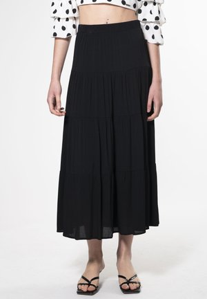 Gonna maxi nera a livello con vita elasticizzata, realizzata in un tessuto leggero, caratterizzata da una consistenza morbida e un design fluido.