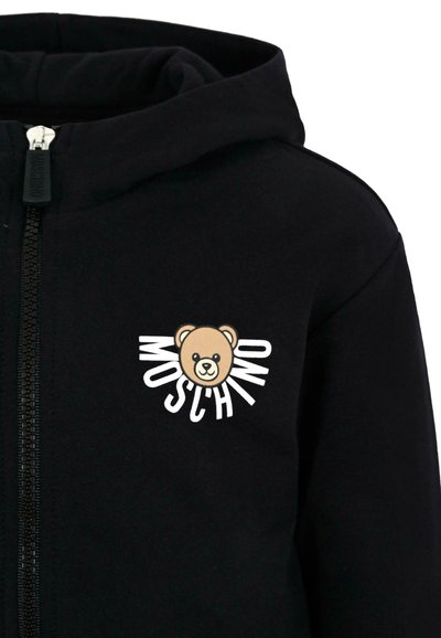 Felpa nera con zip realizzata in cotone, caratterizzata da un grafico di un orso rotondo con il testo "MOSCHINO" in bianco. Texture liscia e design casual.