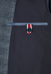 Marineblauw en grijs geblokt vest met een gestroomlijnd ontwerp, voorzien van een knoopzak met gestreepte accent en contrasterende rand.