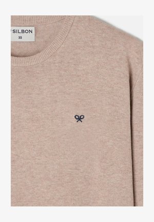 Suéter de punto beige con cuello redondo, puños acanalados y un pequeño emblema de tijeras en azul marino en el pecho. Textura suave y diseño sencillo.