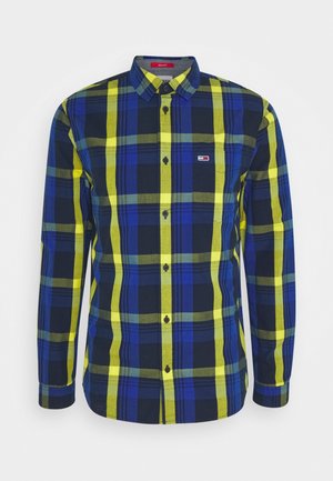 Camisa de manga larga con botones, estampado a cuadros en azul, amarillo y negro, cuello puntiagudo, bolsillo en el pecho delantero y pequeño logo en el lado izquierdo.
