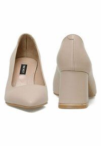 Kerged beezhvärvi kõrged kontsad, millel on sile sädelus, ümar nokk ja plokk-kontsade kujundus, millel on kuldne aksent tallal.