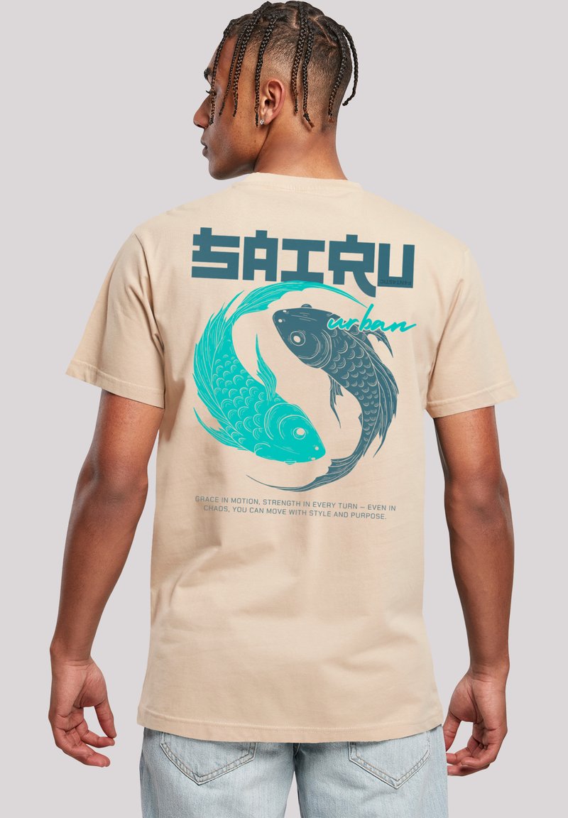 Beige cotton t-shirt featuring a graphic design of two stylized koi fish in turquoise and black. Text reads "SAIRTU urban" above the fish.