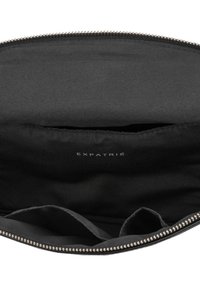 Black zippered pouch made of soft fabric, featuring a smooth interior with multiple compartments and the logo "EXPATRIÉ" printed inside.