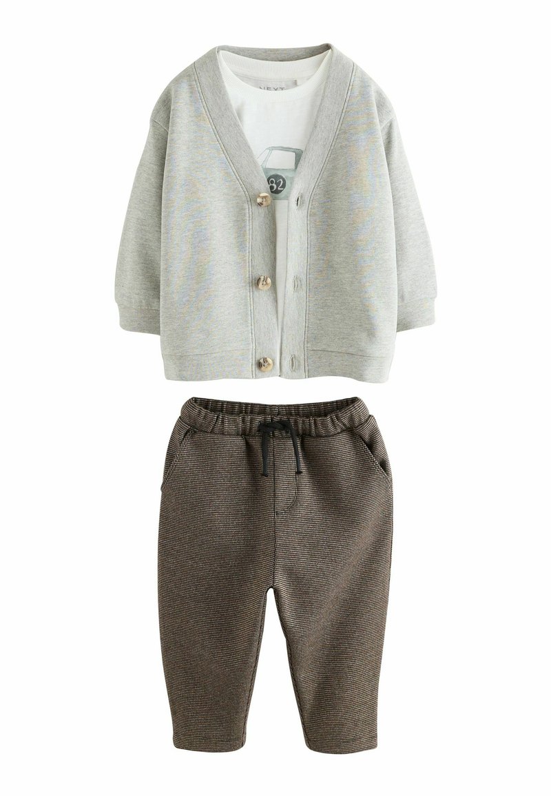 Grijze katoenen cardigan met houten knopen over een witte T-shirt met een autografiek. Bruine gebreide joggers met elastische tailleband en zakken.