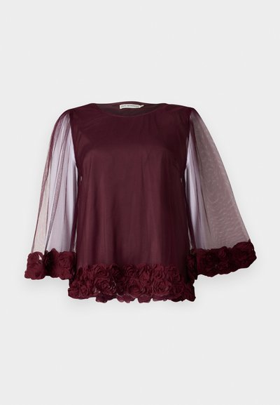 Blusa bordeaux con maniche trasparenti a palloncino. Orlo decorato con rose di stoffa, creando un effetto testurizzato. Tessuto del corpo liscio. Collo rotondo.