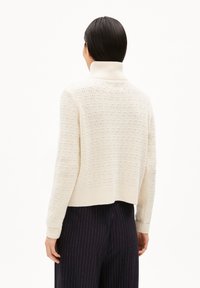Maglione in maglia color crema con colletto alto, caratterizzato da un motivo testurizzato e un design corto. Polsini e orlo a coste.