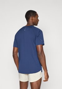 Ναυτικό μπλε αθλητικό μπλουζάκι με κοντά μανίκια, στρογγυλή λαιμόκοψη και διακριτική ραφή στην πλάτη και τα μανίκια. Ελαφρύ ύφασμα.