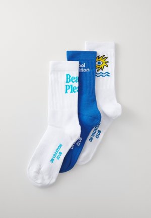 Three pairs of crew socks: one white with "Beach Pleas" in turquoise, one blue with "Cool Nutrition" in white, and one white with sun and wave design.
