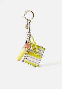 Keychain with a large gold ring, white leather strap, mini spiral notebook with yellow stripes, oversized yellow paperclip, and yellow lip balm.