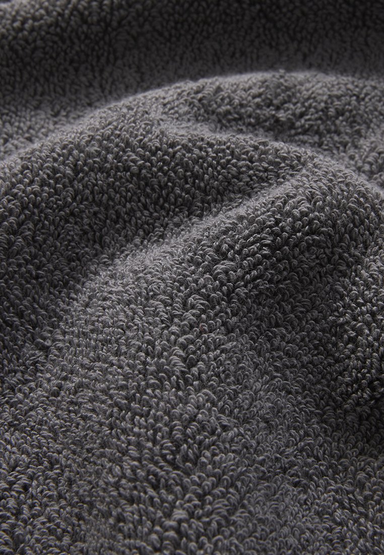Grå frottétyg med en texturerad yta som har täta öglor och skapar ett mjukt, plyschigt utseende.