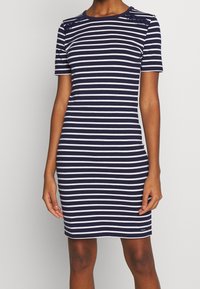 Sukienka w paski w kolorze granatowym i białym, z krótkimi rękawami, okrągłym dekoltem i koronkowym detalem na ramionach. Dopasowany fason, wykonana z gładkiego materiału.