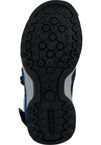 Suela de zapato de goma negra con patrones redondeados y bordes estriados, que presenta un logotipo y una marcación de tamaño. Diseñada para ofrecer tracción y durabilidad.
