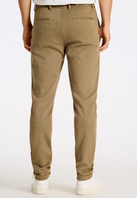 Pantaloni jogger khaki in un morbido tessuto testurizzato, con gamba affusolata e polsini elasticizzati. Presentano tasche posteriori e dettagli di cucitura minimi.