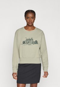 Ανοιχτό πράσινο φούτερ από μαλακό ύφασμα, με λεπτομερή αρχιτεκτονική γραφική απεικόνιση. Το στυλ είναι χαλαρό, με ριμπ μανσέτες και στρίφωμα.