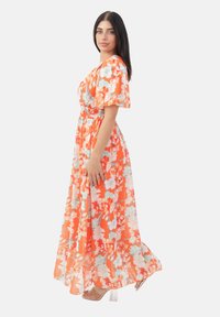 Robe maxi avec un motif floral en orange et bleu clair, en tissu léger, à manches courtes, taille cintrée et jupe fluide.