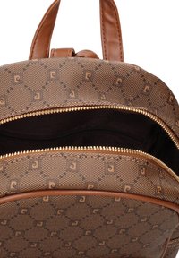 Bruine rugzak met patroon en leren accenten, voorzien van een ritsopening die een zwart binnenvoering en een binnenvak onthult.