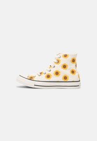 Zapatillas de lona altas blancas con estampado de girasoles amarillos, suela de goma negra y diseño de encaje con cinco ojales. Punta clásica y detalles de costura.