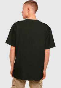 Svart oversized t-skjorte med kort erm, rund halslinning og en jevn tekstur. Synlig søm langs nederkantene.